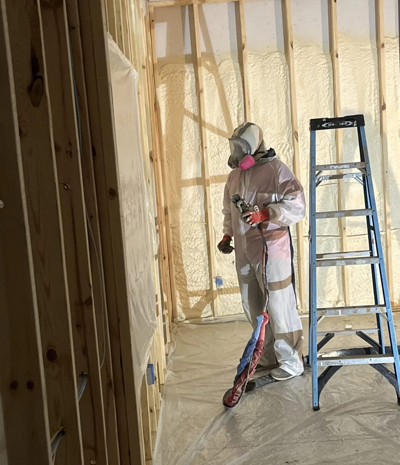 Spray foam contractor applying insulation between wall studs